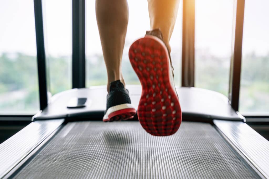 Male feet in sneakers running on the treadmill at the gym. Exercise concept - Podologie Stéphanie Van Wesepoel - diabetesscreening - ganganalyse & biomechanisch onderzoek - voetklachten - voetzorg - terugbetaling podologie - contact